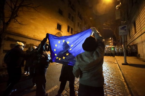 Demonstrators hold an EU flag in front of a police block rallying outside the parliament's building to continue protests against the government's decision to suspend negotiations on joining the European Union in Tbilisi, Georgia, on Monday, Dec. 2, 2024.(AP Photo/Zurab Tsertsvadze)