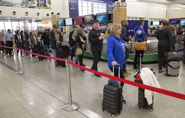 Kim LaFleur (CQ from Connecticut) waits for a friend as multiple security lines at Hartsfield-Jackson International Airport ran across the atrium then snaked through baggage claim in both domestic terminals on Monday February 4th, 2019. Official expected over 100,00 travelers to pass through the airport today. (Photo by Phil Skinner)