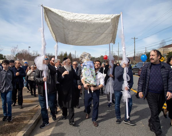 Men take turns marching down Lower Roswell Road, holding the special Torah scroll during a parade celebrating its completion at Chabad of Cobb on Sunday, March 8, 2020.   (Photo: STEVE SCHAEFER / SPECIAL TO THE AJC)