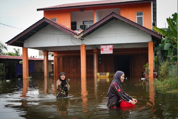 Residents wade through flood water outside their home in Tumpat, outskirts of Kota Bahru, Malaysia, Tuesday, Dec. 3, 2024. (AP Photo/Vincent Thian)