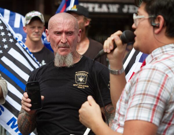 Chester Doles (left), the principal rally organizer, listens to Jovi Val speak to a small crowd in Dahlonega on Saturday,  September 14, 2019.  STEVE SCHAEFER / SPECIAL TO THE AJC