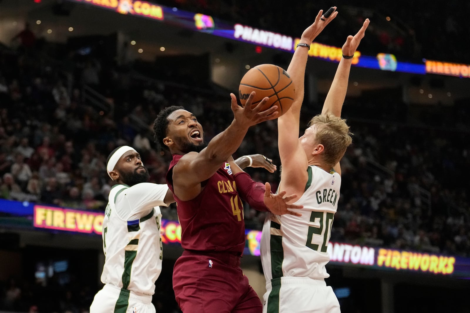 Cleveland Cavaliers guard Donovan Mitchell (45) shoots between Milwaukee Bucks forward Bobby Portis Jr., left, and guard AJ Green (20) in the first half of an NBA basketball game, Monday, Nov. 4, 2024, in Cleveland. (AP Photo/Sue Ogrocki)