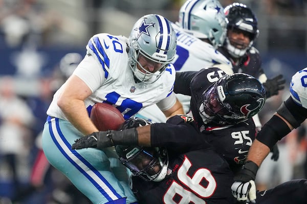 Dallas Cowboys quarterback Cooper Rush (10) tries to avoid being stopped by Houston Texans defensive end Denico Autry (96) and defensive end Derek Barnett (95) during the second half of an NFL football game, Monday, Nov. 18, 2024, in Arlington, Texas. (AP Photo/Tony Gutierrez)