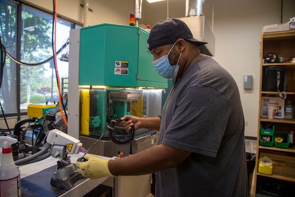 Fischer Connectors employee Marc Eason wears a face mask while preparing a cable during his shift at the company's manufacturing plant in Alpharetta on Monday. (Alyssa Pointer/Atlanta Journal Constitution)