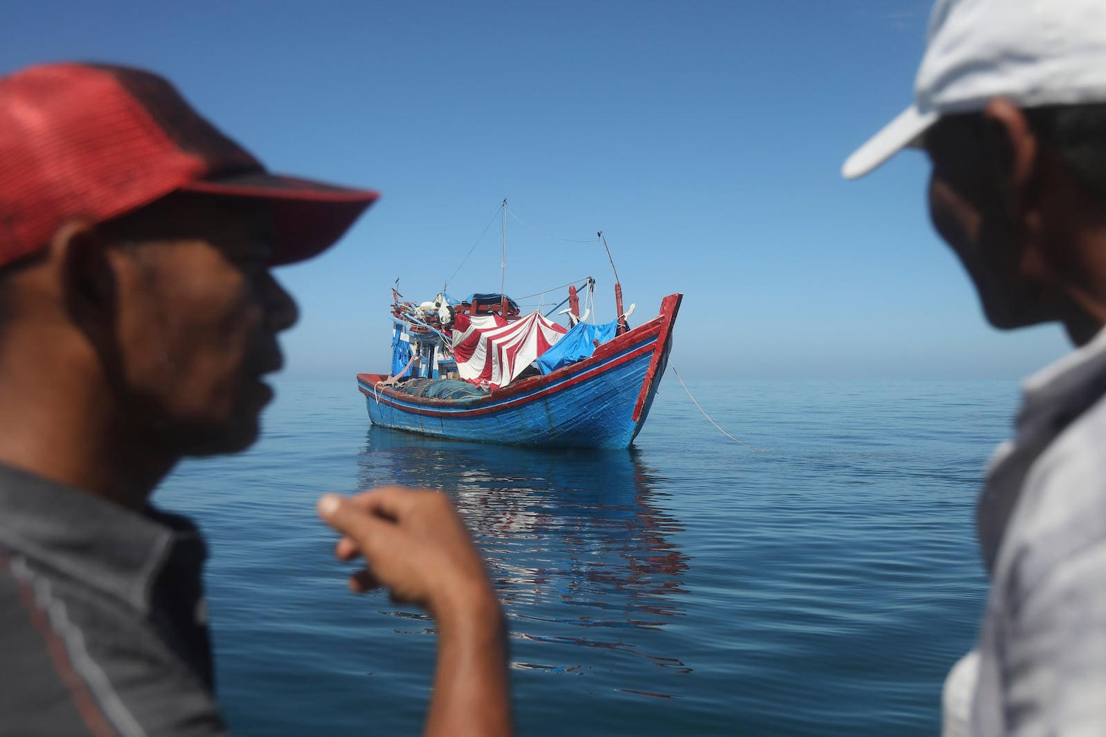 Acehnese men inspect a boat carrying Rohingya refugees anchored in the waters near the coast of Labuhan Haji, Aceh province, Indonesia, Tuesday, Oct. 22, 2024. (AP Photo/Binsar Bakkara)