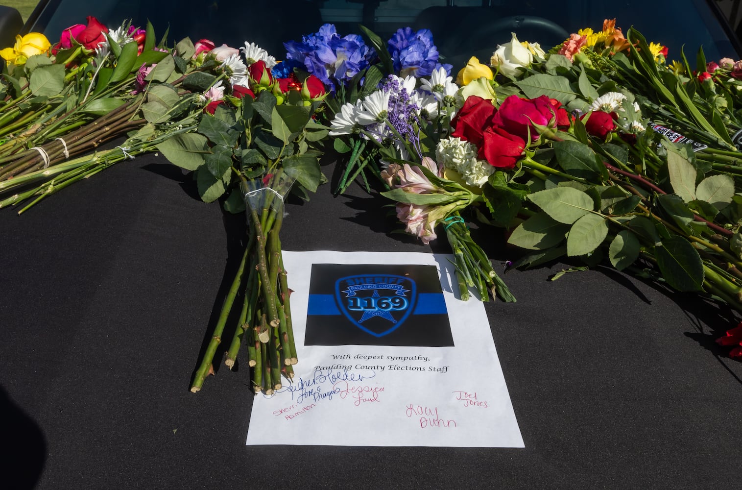 Notes and flowers left on the patrol car parked in front of the Paulding County Sheriff’s department on Monday, Aug. 19, 2024. Deputy Brandon Cunningham was the first Paulding deputy killed in the line of duty. “The patrol car is here to give our community a place to publicly mourn,” Major Ashley Henson said. (John Spink/AJC)