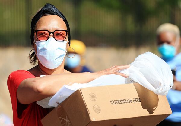 A woman who wished not to be named carries a box of donated food during the Grab and Go free groceries event on Friday, April 17, 2020, at Allen Hills Apartments in Atlanta, which was organized to help families during the coronavirus pandemic. (Christina Matacotta, for The Atlanta Journal-Constitution)