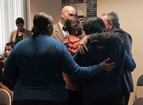 APD homicide commander Capt. Paul Guerrucci (far right) embraces Sadria Strong (center, in orange sweater), mother of murder victim Briana Brooks, as friends and other family members gather around her in an emotional moment on Friday, Oct. 17, 2014. Fulton County District Attorney Paul Howard said Friday he will seek the death penalty for two men suspected of kidnapping and killing a young DeKalb County couple. He also said the men may be connected to seven other deaths.