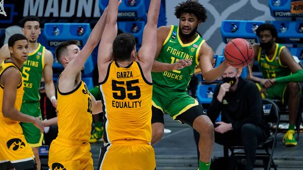 Oregon guard LJ Figueroa (12) passes around Iowa center Luka Garza (55) during the second half of a men's college basketball game in the second round of the NCAA tournament at Bankers Life Fieldhouse in Indianapolis, Monday, March 22, 2021. (AP Photo/Paul Sancya)