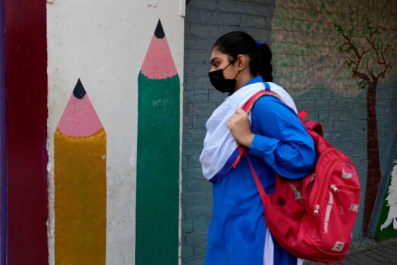 A student wears mask to protect herself from poor air quality due to increasing smog in the city as she heads to school, in Lahore, Pakistan, Monday, Nov. 4, 2024. (AP Photo/K.M. Chaudary)