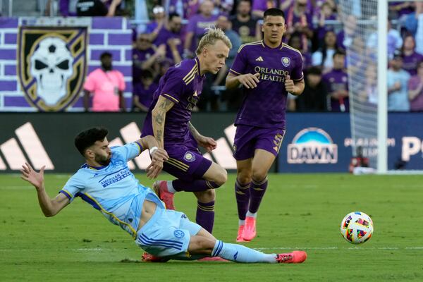 Atlanta United's Pedro Amador, left, clears the ball away from Orlando City's Dagur Thorhallsson, center, and Cesar Araujo (5) during the first half of an MLS Semifinal Conference playoff soccer match, Sunday, Nov. 24, 2024, in Orlando, Fla. (AP Photo/John Raoux)