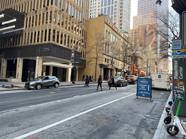 Pedestrians crossing Peachtree Street on Monday at the location of a crosswalk that was removed by the city after a pedestrian death. AJC