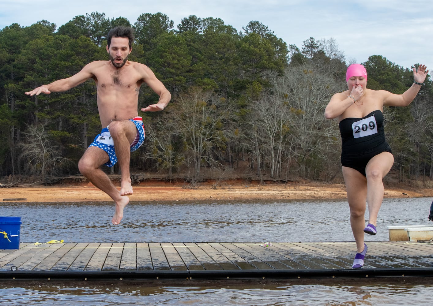 Adam Stephens and Katie Sanders of Johns Creek, participate in the 26th annual Polar Bear Paddle and Plunge at Lake Lanier Olympic Park on Monday, Jan 1, 2024.  (Jenni Girtman for The Atlanta Journal-Constitution)