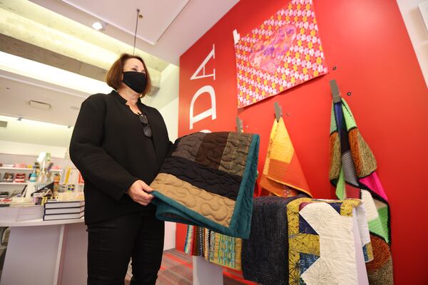 Atlanta Design Museum Executive Director Laura Flusche  shows one of the blankets donated to the Warm Blanket Project on Nov. 10, 2021.  The museum plans to collect hundreds of blankets through the Welcome Blanket Project to deliver to Afghan refugees who will soon arrive in Georgia. Miguel Martinez for The Atlanta Journal-Constitution.