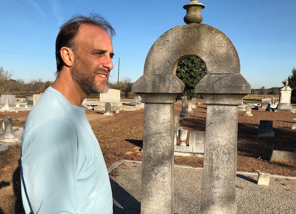 The Rev. Alan Davis Jenkins, who lives in Decatur, but whose family has owned land near Rutledge in Morgan County since the early 1800s, stands in a family cemetery on Dec. 3, 2021, along Davis Academy Road. Jenkins wants to build a home and organic farm on family land near Rutledge and is opposed to a Rivian electric vehicle plant that could be built nearby on about 2,000 acres between Rutledge and Social Circle. J. SCOTT TRUBEY/STAFF