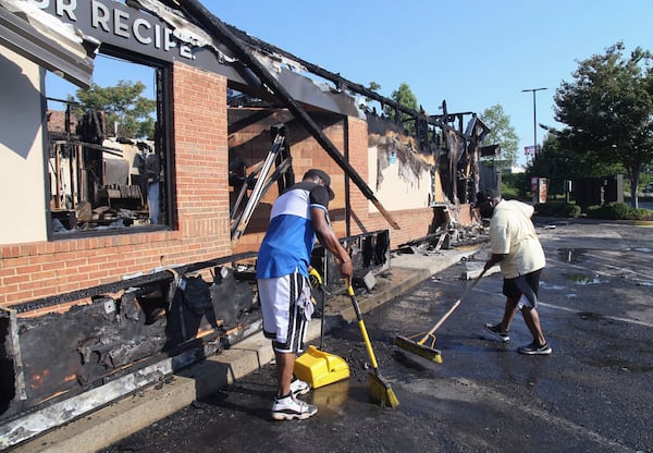 Renault Verona (left) and other area residents came on their own to help clean up Sunday after a fire gutted the Wendy’s where Rayshard Brooks was shot.