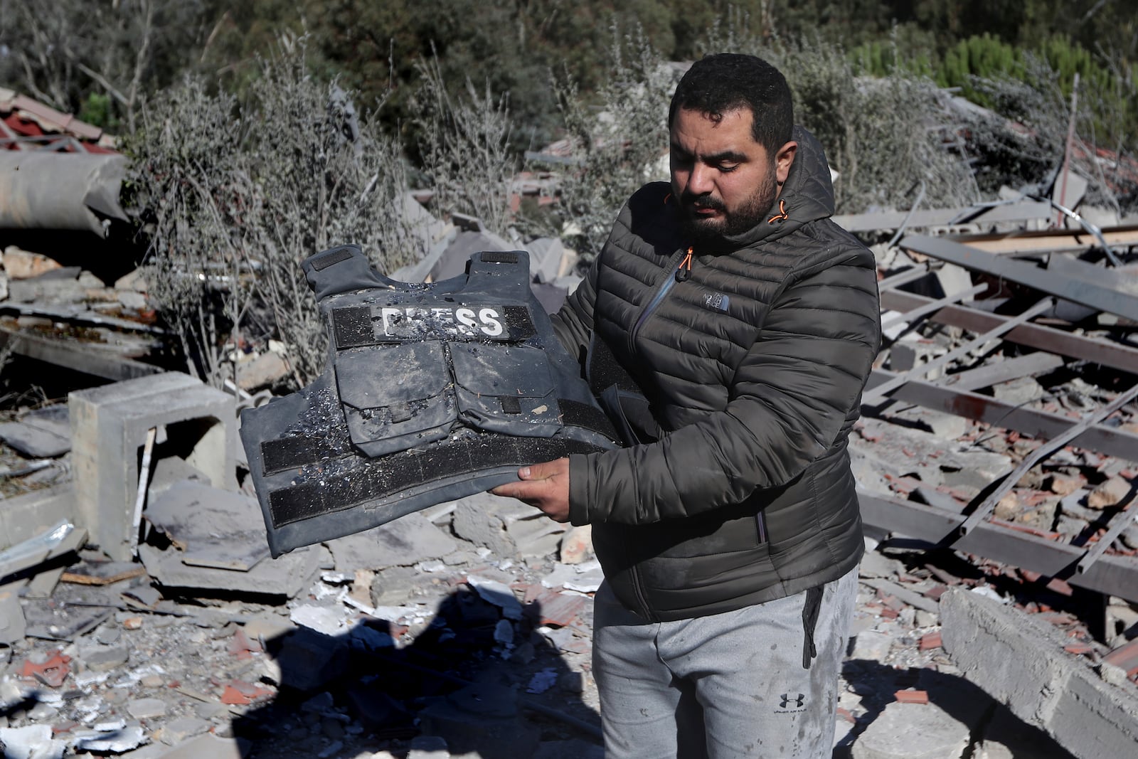 A journalist carries the flack jacket, at the site where an Israeli airstrike hit a compound housing journalists, killing three media staffers from two different news agencies according to Lebanon's state-run National News Agency, in Hasbaya village, southeast Lebanon, Friday, Oct. 25, 2024. (AP Photo/Mohammed Zaatari)