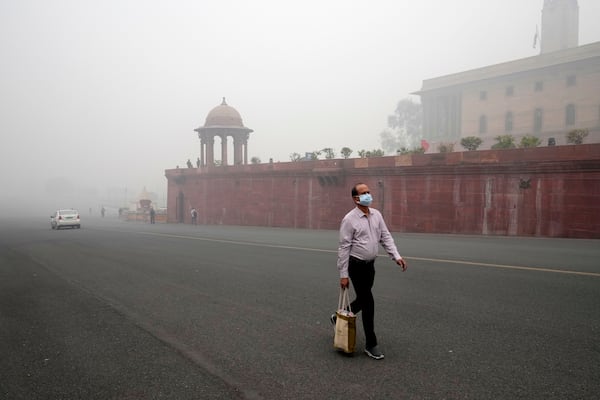 A office goer walks wearing a face mask amidst a thick layer of smog as air pollution shoots up in New Delhi, India, Monday, Nov. 18, 2024. (AP Photo/Manish Swarup)