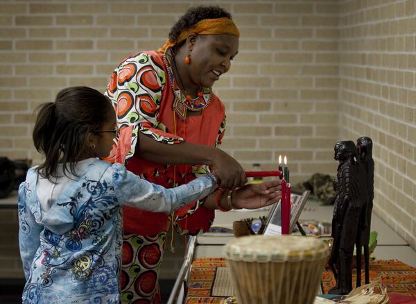 Elizabeth Kahura helps Lauryn Whitlock, 9, light a Kwanzaa candle at a Kwanzaa celebration at the Carver Museum. Jay Janner/AMERICAN-STATESMAN 2010