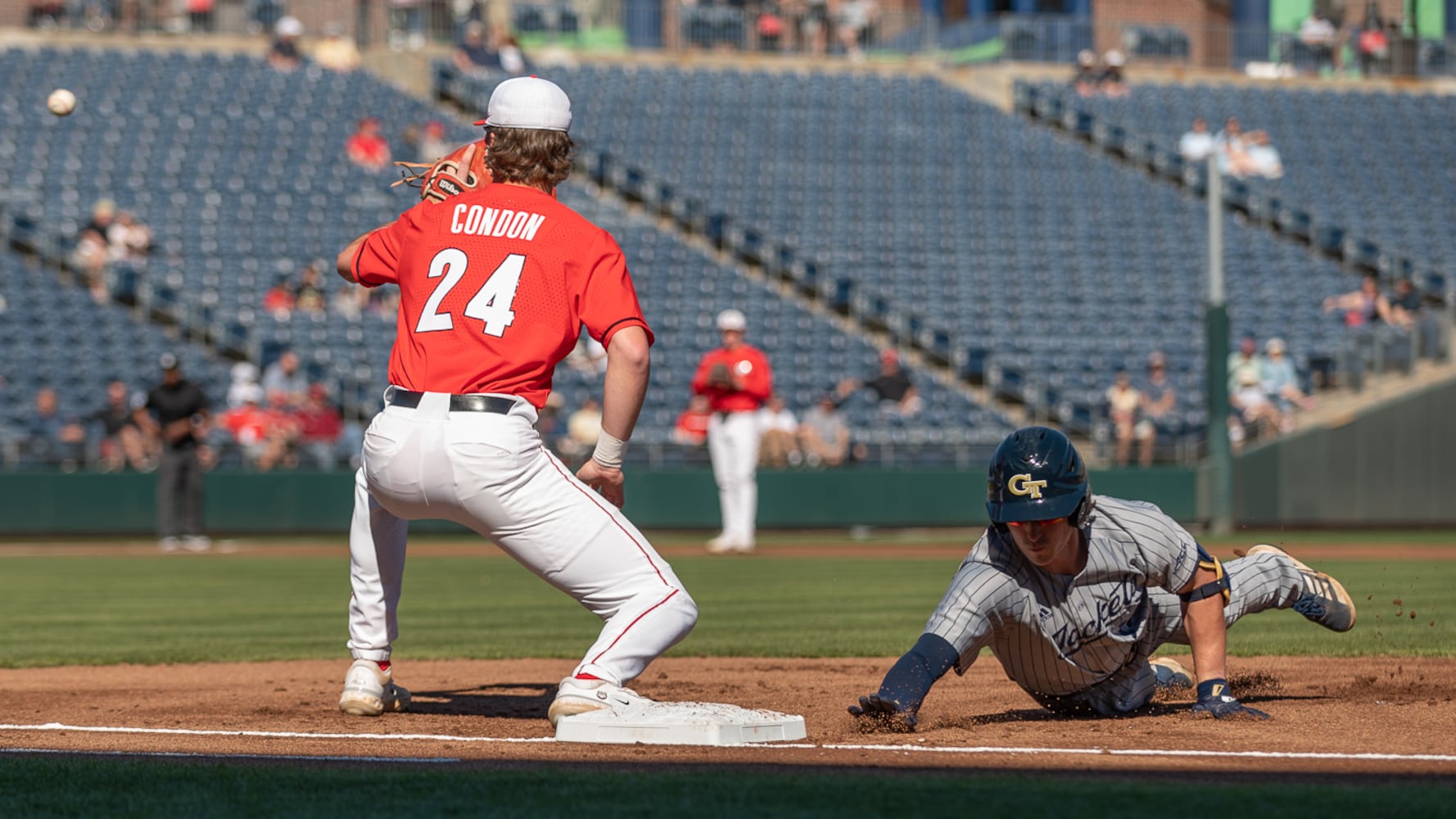 Georgia Tech's Jake DeLeo dives back to first as Bulldogs first baseman Charlie Condon awaits the throw during the 20th Spring Classic game on Sunday at Coolray Field in Lawrenceville. (Jamie Spaar / for The Atlanta Journal-Constitution)