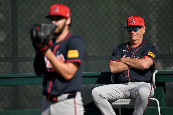 Braves manager Brian Snitker (right) watches pitcher Ian Anderson during a recent spring training workout.