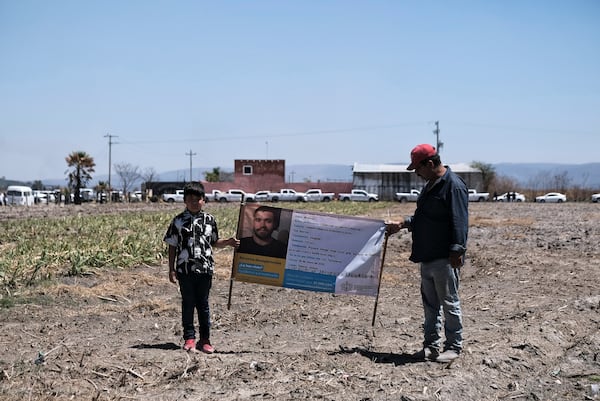 People hold a photo of a missing relative outside Izaguirre Ranch where skeletal remains were discovered in Teuchitlan, Jalisco state, Mexico, Thursday, March 13, 2025. (AP Photo/Alejandra Leyva)