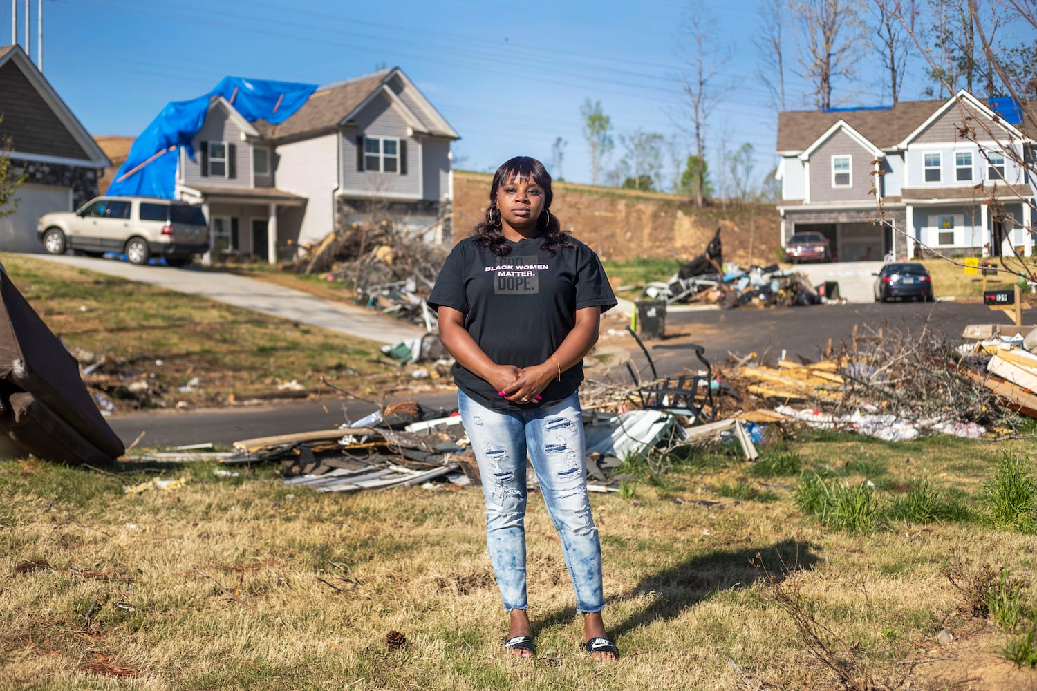 Brittany Mitchell, 30, stands in the midst of damage from an EF4 tornado that ripped through her neighborhood in March and damaged her family’s Newnan home. (Alyssa Pointer / Alyssa.Pointer@ajc.com)