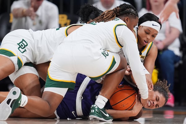 TCU guard Donovyn Hunter, bottom, holds onto the ball as Baylor's Yaya Felder, front, Bella Fontleroy, left, and Sarah Andrews, top right, wrestle on the floor for control in the first half of an NCAA college basketball game in Waco, Texas, Sunday, March 2, 2025. (AP Photo/Tony Gutierrez)