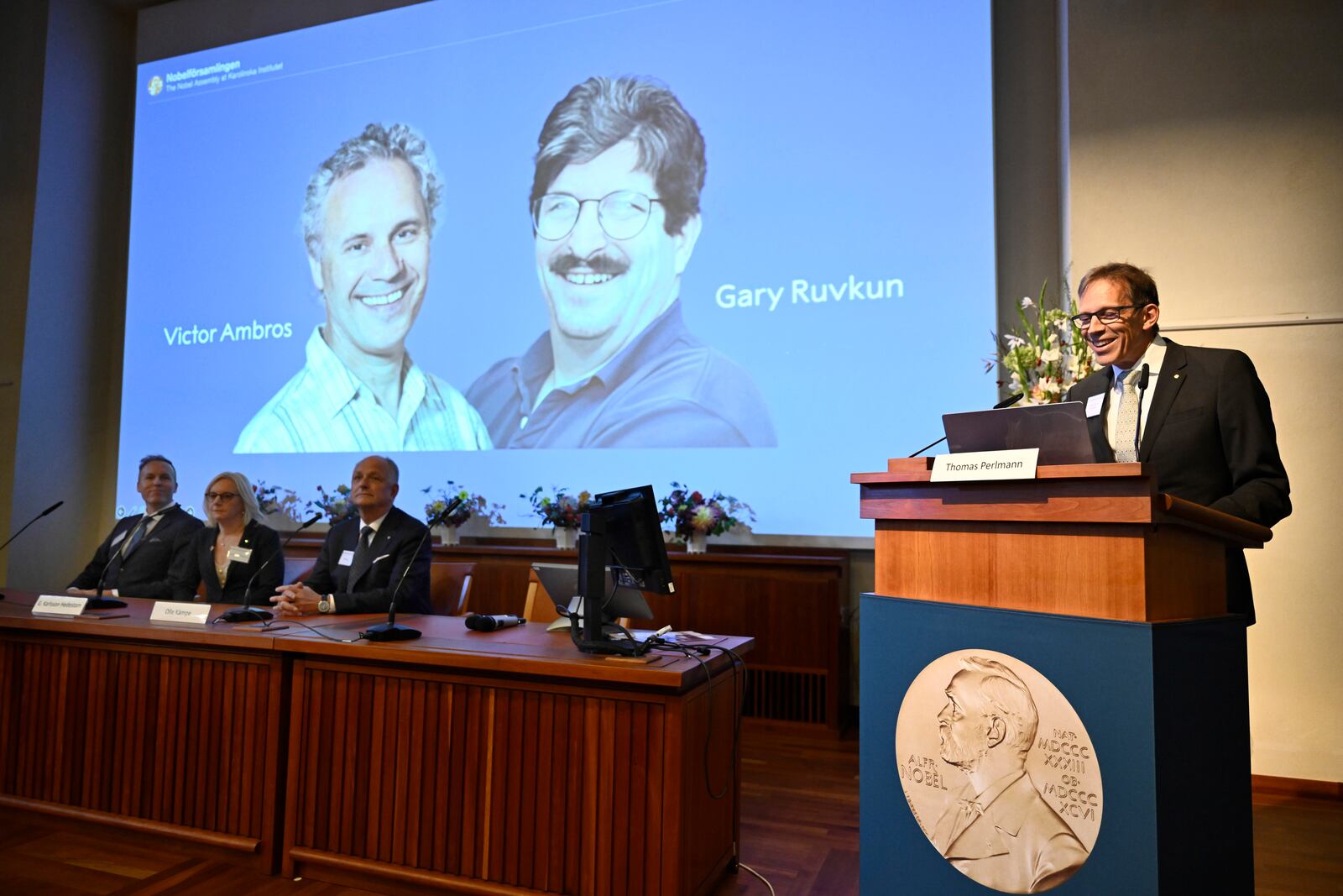 Nobel Committee chairman Thomas Perlmann, right, announces Americans Victor Ambros, left, and Gary Ruvkun, seen on a screen being awarded this year's Nobel Prize in Physiology or Medicine, during a press conference at the Karolinska Institute in Stockholm, Sweden, on Monday, Oct. 7, 2024. (Christine Olsson/TT News Agency via AP)