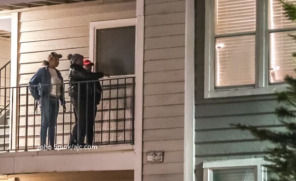 A group inspects the exterior of an apartment where a fatal shooting unfolded just after midnight Thursday.