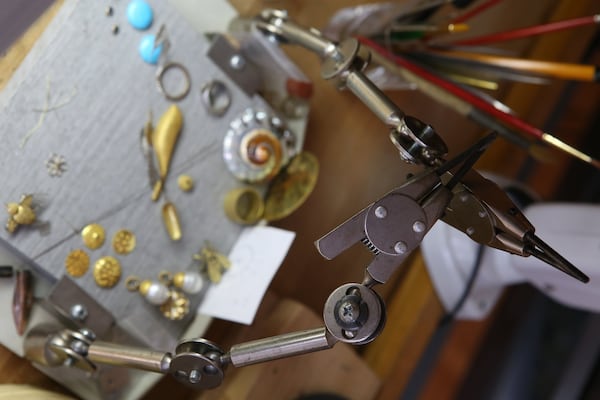 Clamps to make working with gems and metals easier are contorted into an arch above miscellaneous pieces to be used in future jewelry at Kathy Kinev’s workshop in Atlanta. HENRY TAYLOR / HENRY.TAYLOR@AJC.COM