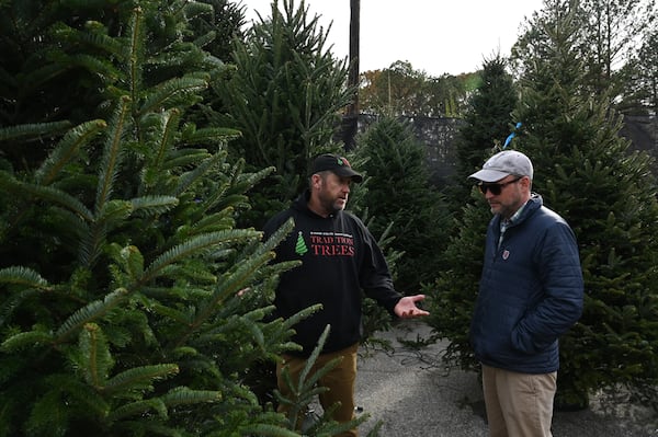 Matt Bowman (left), owner of Tradition Trees, helps customer Hil Rogers choose a Christmas tree.