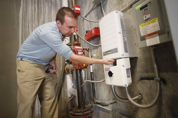 Scott Starowicz, chief financial officer of the SAE School in Mableton, checks the school’s solar power inverter. The inverter converts the DC power from the solar array to AC power that can be used to power the school. BOB ANDRES / ROBERT.ANDRES@AJC.COM