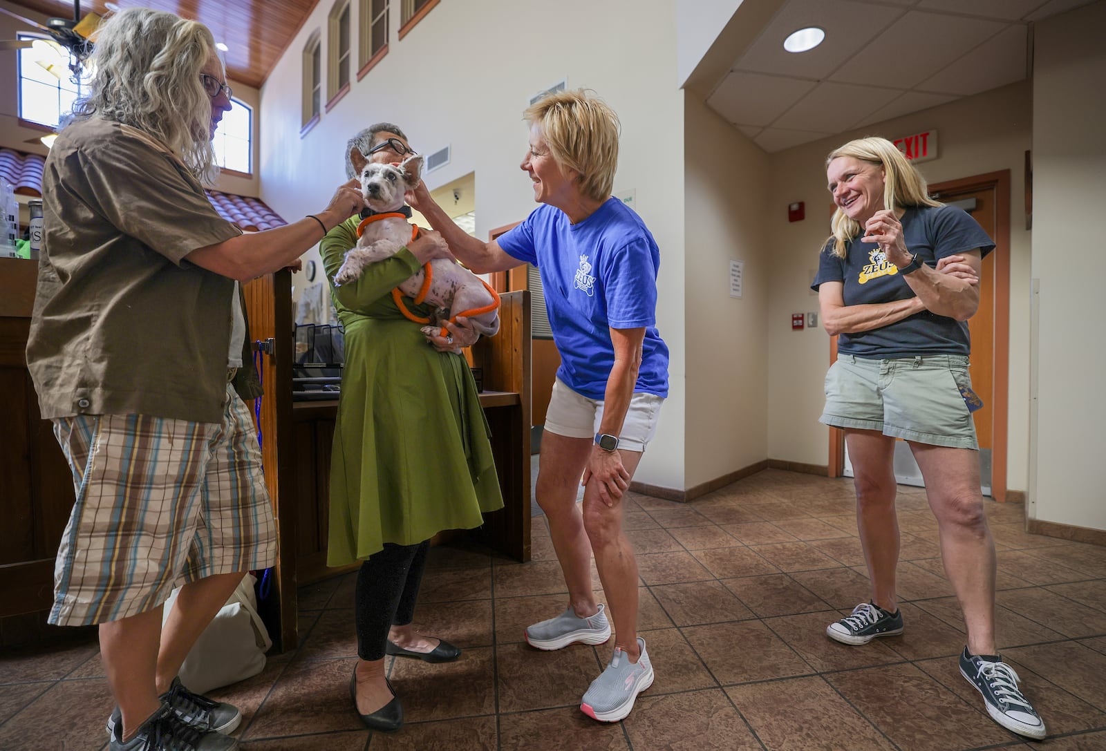 Karen Ocker, Debra Voelker, and Barbara Burger pet Scrim as Michelle Cheramie, far right, looks on at Metairie Small Animal Hospital in Metairie, La., Thursday, Oct. 24, 2024. (Brett Duke/The Times-Picayune/The New Orleans Advocate via AP)