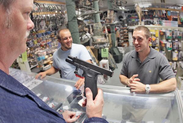  Rob Abrams, left, shows customers a Glock 17 at Adventure Outdoors in Smyrna, where Glock Inc. is headquartered, in this 2010 photo. Massachusetts' attorney general launched a consumer protection investigation into the company last year, even though Glock can't sell directly to consumers there because its guns don't meet state safety requirements. BOB ANDRES BANDRES@AJC.COM