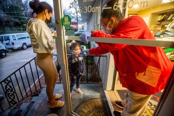 Ashley Strickland (R) takes the temperature of Isabel, 5, as her mother, Adrina Rojas, fills out the form at the Little Ones Learning Center in Forest Park Friday, March 19, 2021.  STEVE SCHAEFER FOR THE ATLANTA JOURNAL-CONSTITUTION