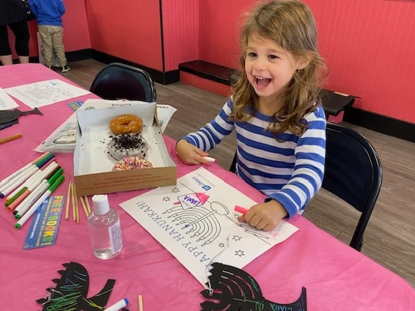 A young girl enjoys doughnuts while coloring a menorah at one of the Donuts and Dreidels events sponsored by the Jewish Federation of Greater Atlanta, PJ Library and JBaby. (Courtesy)