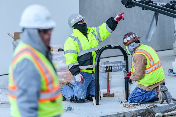 Construction workers Miguel Rizo (from left), Isidor Hernandez and Juan Escandon were bundled up early Friday. They were working on the new Whole Foods Market on Spring Street in Midtown. JOHN SPINK / JSPINK@AJC.COM