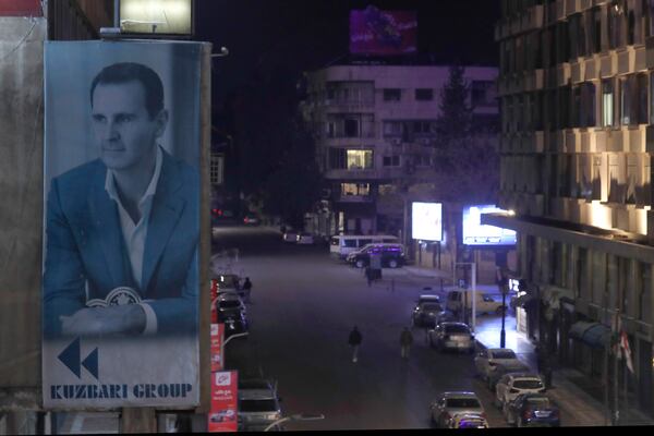 A giant portrait of Syrian president Bashar Assad sets on a building, as empty streets seen in Damascus, Syria, Saturday, Dec. 7, 2024. (AP Photo/Omar Sanadiki)