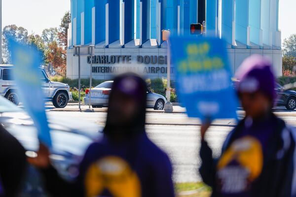 Airport workers wave signs as they march in front of the Charlotte Douglas International Airport in Charlotte, N.C., Monday, Nov. 25, 2024. (AP Photo/Nell Redmond)