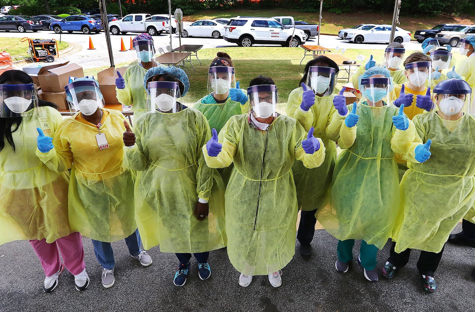 Some of the more than two dozen specimen collection volunteers give the thumbs up as they begin hundreds of free COVID-19 tests at a pop-up site at the House of Hope on May 4, in Decatur. (Curtis Compton/ccompton@ajc.com)