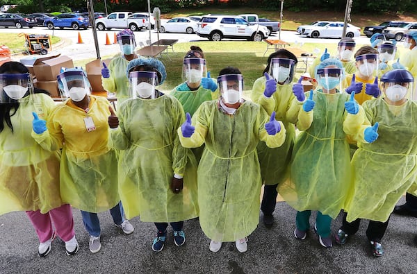 Some of the more than two dozen specimen collection volunteers give the thumbs up as they begin hundreds of free COVID-19 tests at a pop-up site at the House of Hope on May 4, in Decatur. (Curtis Compton/ccompton@ajc.com)