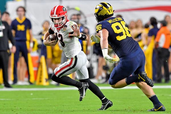 Georgia Bulldogs quarterback Stetson Bennett (13) runs away from Michigan Wolverines defensive lineman Julius Welschof (96) for a gain during the second quarter in the 2021 College Football Playoff Semifinal at the Orange Bowl at Hard Rock Stadium, Friday, in Miami Gardens, Fl. (Hyosub Shin / Hyosub.Shin@ajc.com)