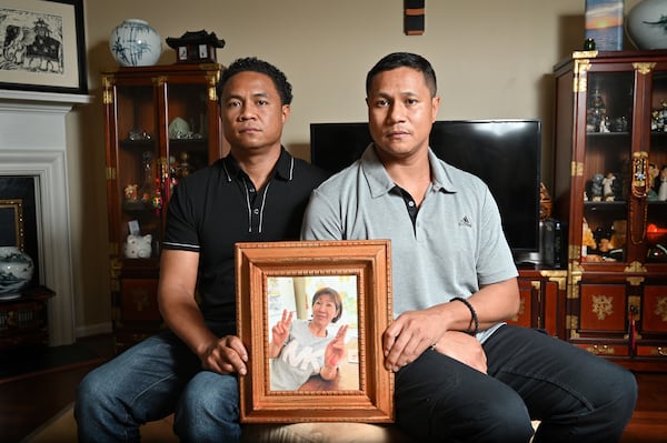 March 31, 2021 Norcross - Robert (left) and Elliott Peterson, sons of one of Atlanta spas shooting victims, hold a portrait of their late mother Yong Ae Yu, in Norcross on Wednesday, March 31, 2021. (Hyosub Shin / Hyosub.Shin@ajc.com)