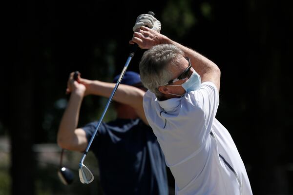 Mike Alberts wears a face mask as he follows through on a practice swing on the driving range at the Haggin Oaks Golf Complex in Sacramento, California. The Sacramento County health director has designated golf as an essential service to the community, allowing the course to stay open during the coronavirus caused shelter-in-place orders. 