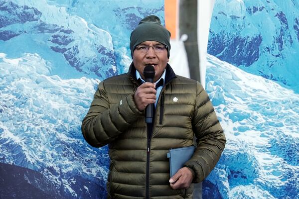 Peruvian farmer Luciano Lliuya speaks to the media in front of glacier pictures held by activists at the Higher Regional Court in Hamm, Germany, before a first hearing of his climate damages case against the German energy company RWE for its carbon emissions, which may have been contributing to the melting of a nearby glacier that could flood his home, Monday, March 17, 2025. (AP Photo/Martin Meissner)