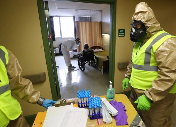 Georgia Army National Guard infection control members Sgt. Daniel Belman (right) and Pfc Cierra Williams (left) with the 265th Chemical Battalion assist Piedmont doctor Stephen Smith in collecting swabs from residents at Legacy Transitional Care to test for COVID-19 in April. Curtis Compton ccompton@ajc.com