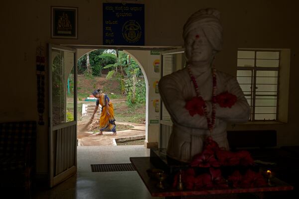 A bust of Indian scholar Swami Vivekananda is displayed inside the common area as a staffer uses a broom to clean the pathway, at the campus of the Swami Vivekananda Youth Movement, a nongovernmental organization that works to help poor and Indigenous communities, in Kenchanahalli, India, Monday, Sept. 23, 2024. (AP Photo/Aijaz Rahi)