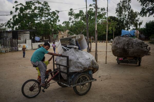 A child carries garbage to recycle on his bicycle in the La Voz que Clama neighborhood, on the outskirts of Maicao, Colombia, Wednesday, Feb. 5, 2025. (AP Photo/Ivan Valencia)