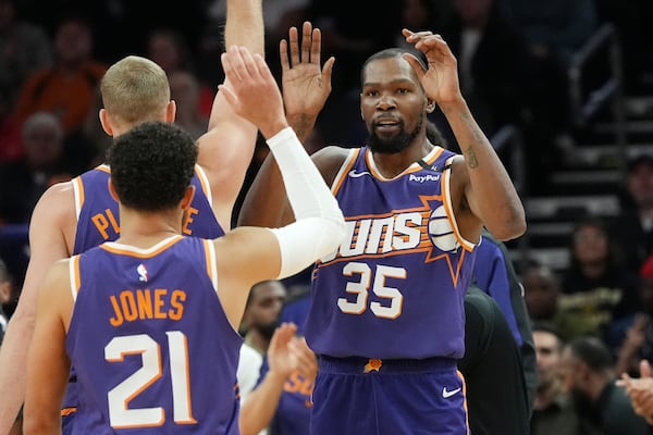 Phoenix Suns forward Kevin Durant (35) celebrates his 3-pointer against the Atlanta Hawks with Suns guard Tyus Jones (21) and Suns center Mason Plumlee during the first half of an NBA basketball game Thursday, Jan. 9, 2025, in Phoenix. (AP Photo/Ross D. Franklin)